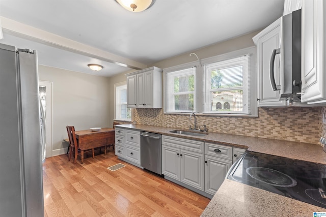 784 80th St, Birmingham, AL 35206 - kitchen with stainless steel appliances, a sink, light wood-style floors, and backsplash