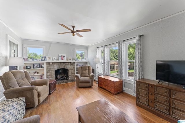 784 80th St, Birmingham, AL 35206 - living area featuring light wood-style floors, ceiling fan, a textured wall, a stone fireplace, and crown molding