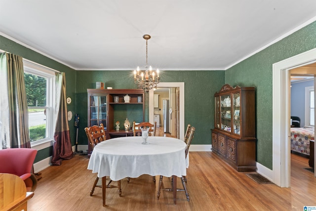 784 80th St, Birmingham, AL 35206 - dining space with ornamental molding, wood finished floors, a chandelier, a textured wall, and baseboards