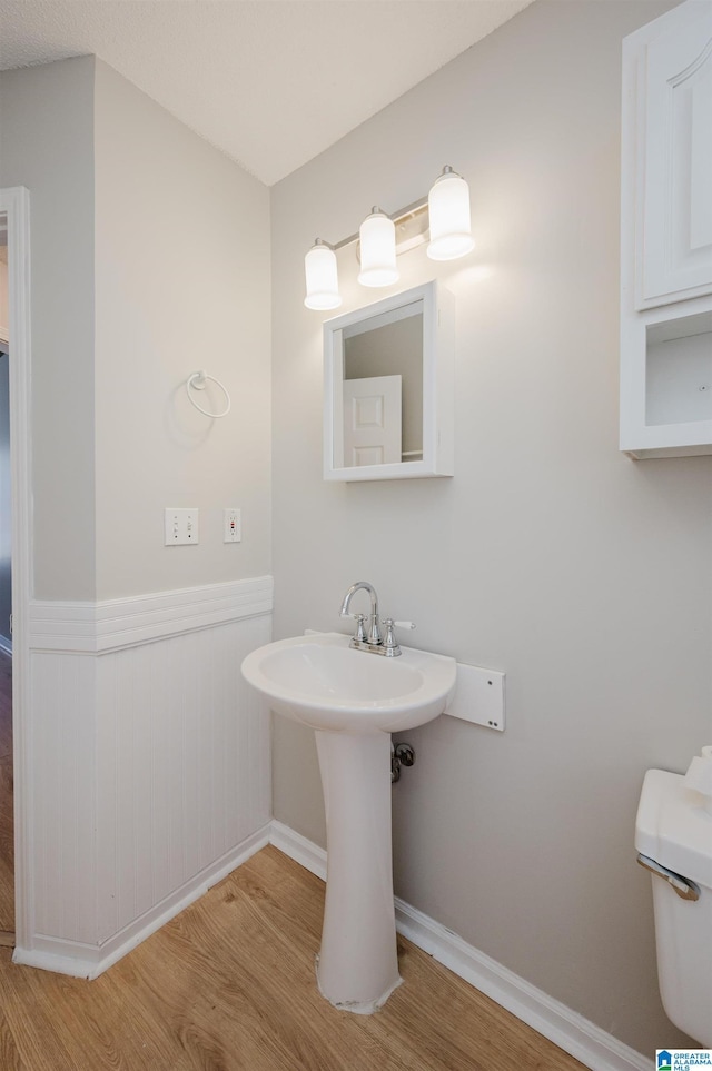 1012 Hickory St, Moody, AL 35004 - bathroom with wood finished floors, a wainscoted wall, toilet, baseboards, and a sink