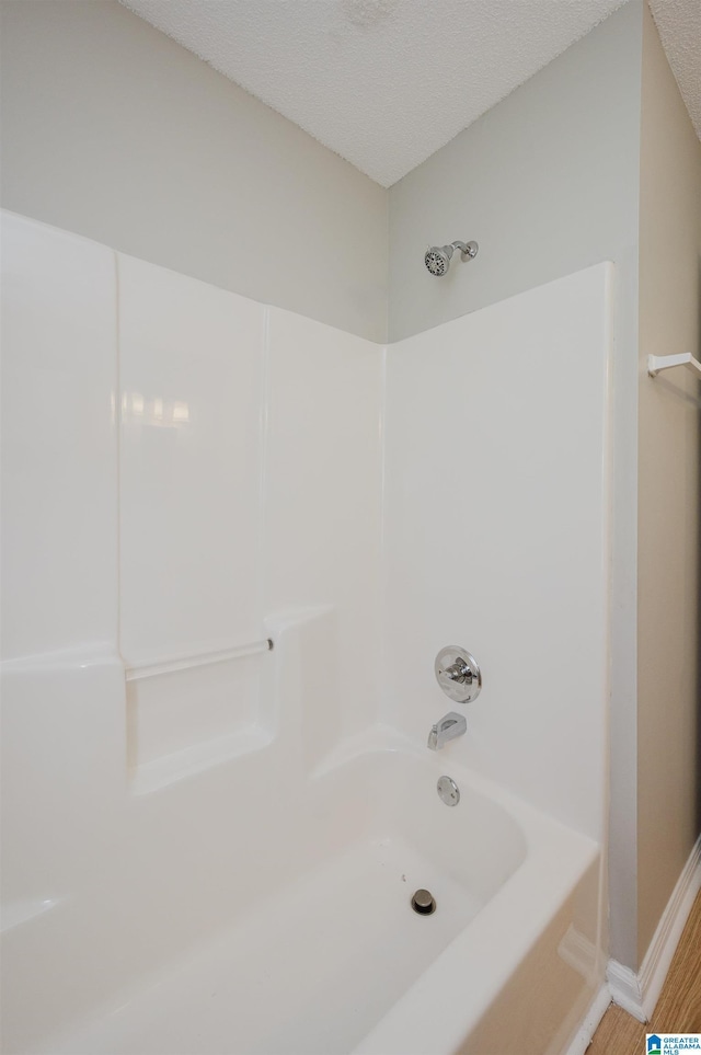 1012 Hickory St, Moody, AL 35004 - bathroom featuring baseboards, wood finished floors,  shower combination, and a textured ceiling