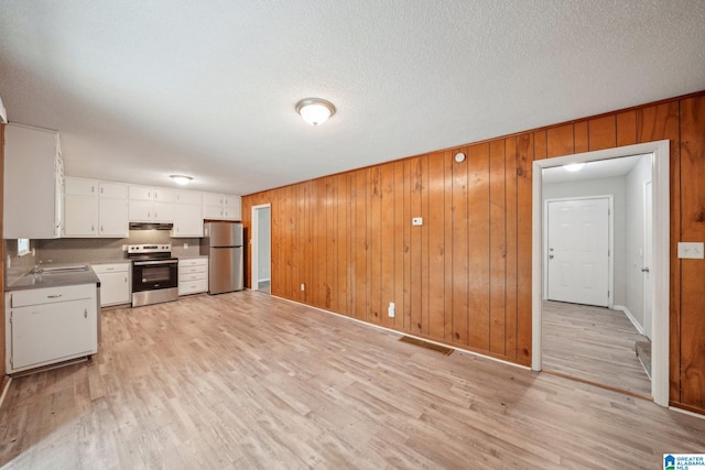 1716 Nancy Ln, Center Point, AL 35215 - kitchen with stainless steel appliances, light wood-style floors, white cabinets, wooden walls, and under cabinet range hood