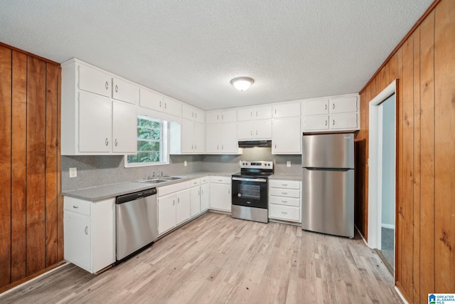 1716 Nancy Ln, Center Point, AL 35215 - kitchen with appliances with stainless steel finishes, light wood finished floors, under cabinet range hood, wood walls, and a textured ceiling