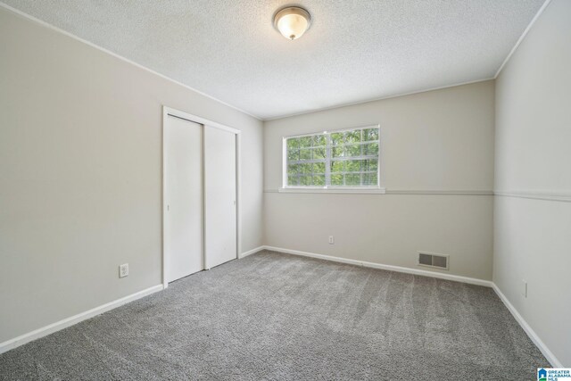 1716 Nancy Ln, Center Point, AL 35215 - unfurnished bedroom with carpet, a textured ceiling, a closet, and baseboards