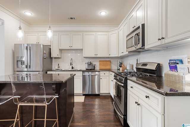 1517 Laurens St, Birmingham, AL 35242 - kitchen with appliances with stainless steel finishes, decorative backsplash, a breakfast bar area, a sink, and dark wood-type flooring