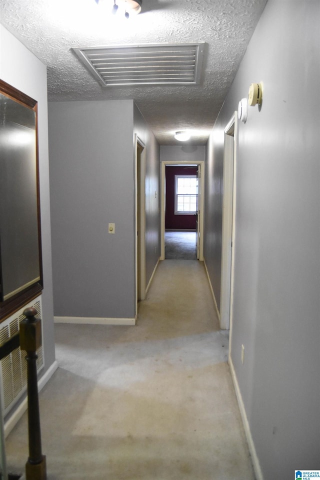 2301 Hathaway Heights Rd, Anniston, AL 36207 - hall featuring a textured ceiling, baseboards, light carpet, and attic access
