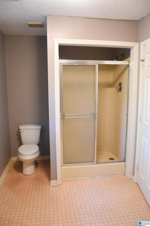 2301 Hathaway Heights Rd, Anniston, AL 36207 - bathroom featuring toilet, a shower stall, baseboards, and a textured ceiling