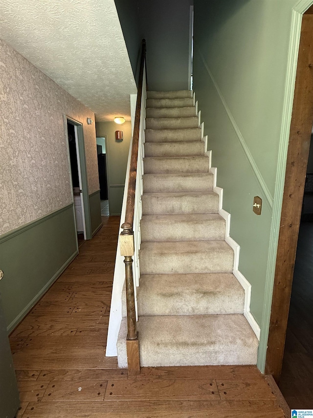 2301 Hathaway Heights Rd, Anniston, AL 36207 - stairs with wood finished floors, a textured ceiling, and baseboards