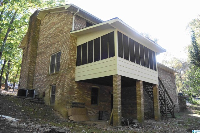 2301 Hathaway Heights Rd, Anniston, AL 36207 - view of side of property with brick siding, a sunroom, stairs, and central AC
