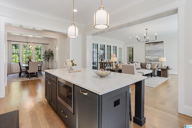 3 Troon, Birmingham, AL 35242 - kitchen with stainless steel microwave, a chandelier, crown molding, light wood finished floors, and pendant lighting