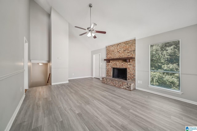 1056 Cardinal Cir, Hueytown, AL 35023 - unfurnished living room featuring high vaulted ceiling, wood finished floors, a ceiling fan, baseboards, and a brick fireplace