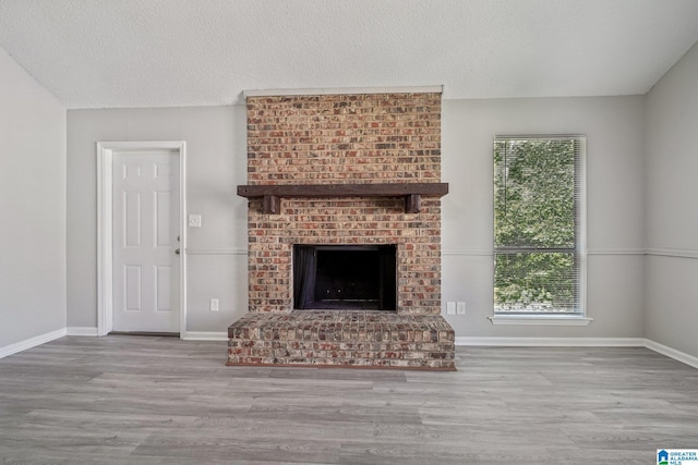 1056 Cardinal Cir, Hueytown, AL 35023 - unfurnished living room with a brick fireplace, wood finished floors, baseboards, and a textured ceiling
