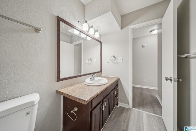1056 Cardinal Cir, Hueytown, AL 35023 - half bathroom with vanity, wood finished floors, toilet, baseboards, and a textured ceiling