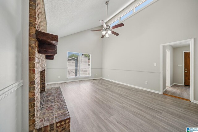 1056 Cardinal Cir, Hueytown, AL 35023 - unfurnished living room featuring ceiling fan, wood finished floors, high vaulted ceiling, a fireplace, and baseboards