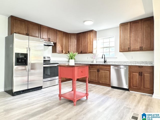 2723 6th St NE, Center Point, AL 35215 - kitchen featuring stainless steel appliances, under cabinet range hood, light wood-style flooring, a sink, and brown cabinets