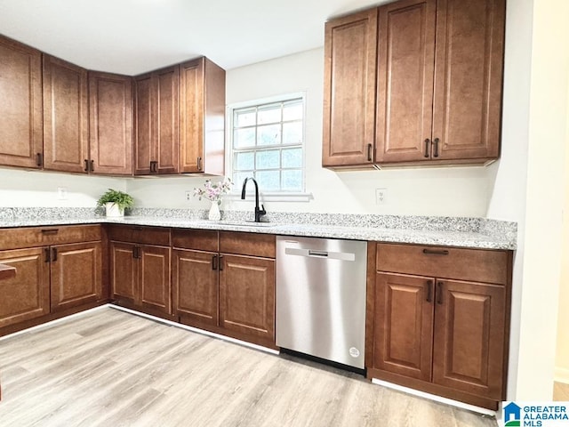 2723 6th St NE, Center Point, AL 35215 - kitchen with stainless steel dishwasher, light wood-style floors, light stone countertops, a sink, and brown cabinetry