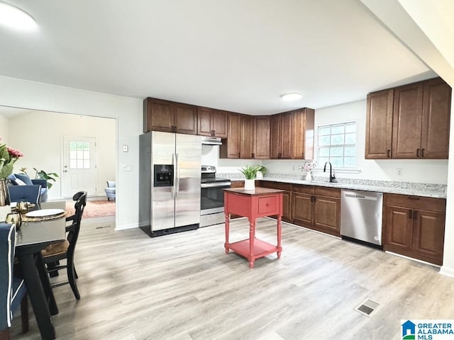 2723 6th St NE, Center Point, AL 35215 - kitchen featuring appliances with stainless steel finishes, under cabinet range hood, light wood finished floors, and healthy amount of natural light