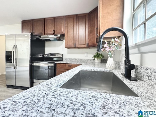 2723 6th St NE, Center Point, AL 35215 - kitchen featuring stainless steel appliances, under cabinet range hood, a sink, light wood-type flooring, and light stone countertops