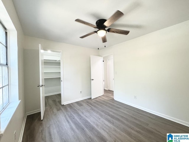 2723 6th St NE, Center Point, AL 35215 - unfurnished bedroom featuring dark wood-style floors, a spacious closet, baseboards, a ceiling fan, and a closet