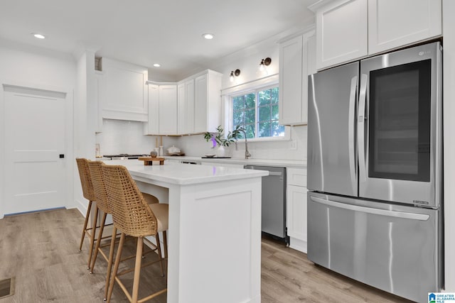 1505 36th St N, Birmingham, AL 35234 - kitchen featuring appliances with stainless steel finishes, a kitchen island, decorative backsplash, light wood-style floors, and recessed lighting
