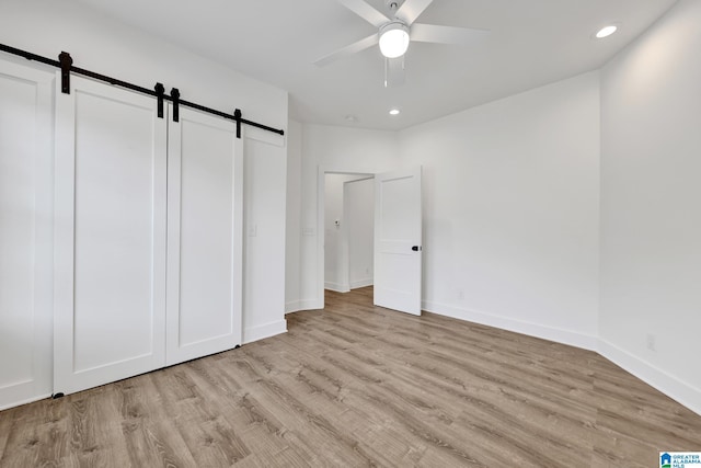 1505 36th St N, Birmingham, AL 35234 - unfurnished bedroom with a barn door, light wood-type flooring, recessed lighting, baseboards, and ceiling fan