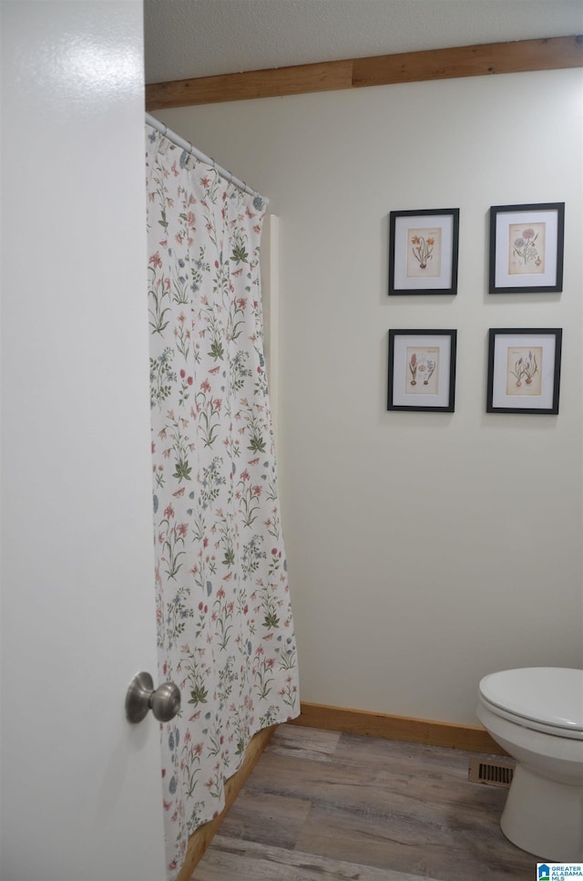1679 Curry Hwy, Jasper, AL 35503 - bathroom featuring toilet, wood finished floors, beam ceiling, a shower with shower curtain, and baseboards