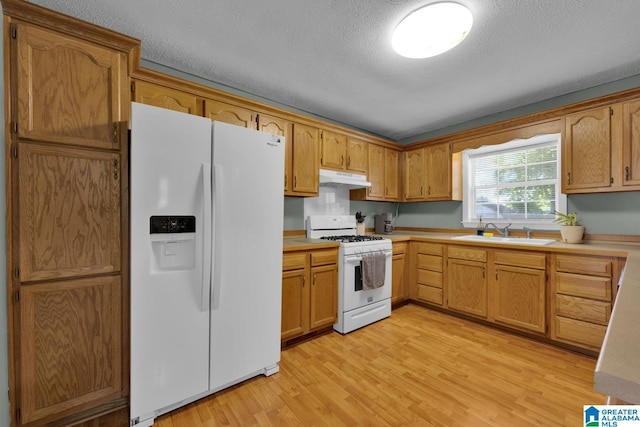 1416 11th St SE, Cullman, AL 35055 - kitchen featuring white appliances, under cabinet range hood, a sink, light wood-style floors, and light countertops
