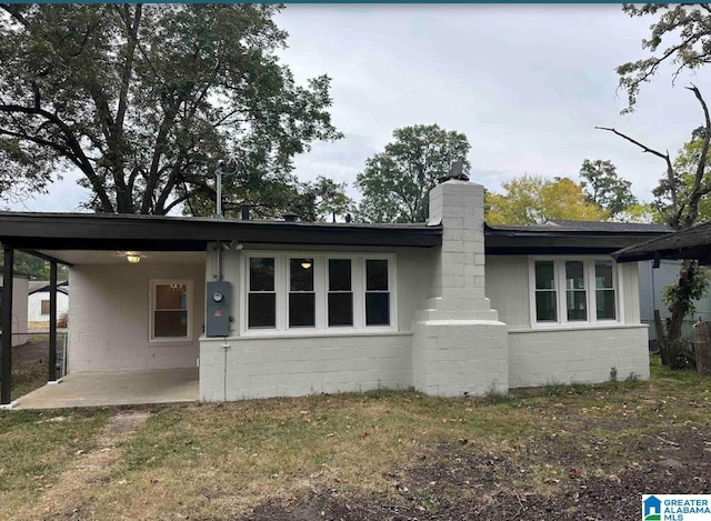 1861 Woodland Ave SW, Birmingham, AL 35211 - rear view of house featuring concrete block siding, a chimney, an attached carport, and a patio area