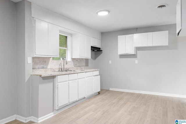 1232 Frisco St, Birmingham, AL 35224 - kitchen featuring light countertops, light wood finished floors, white cabinetry, and a sink