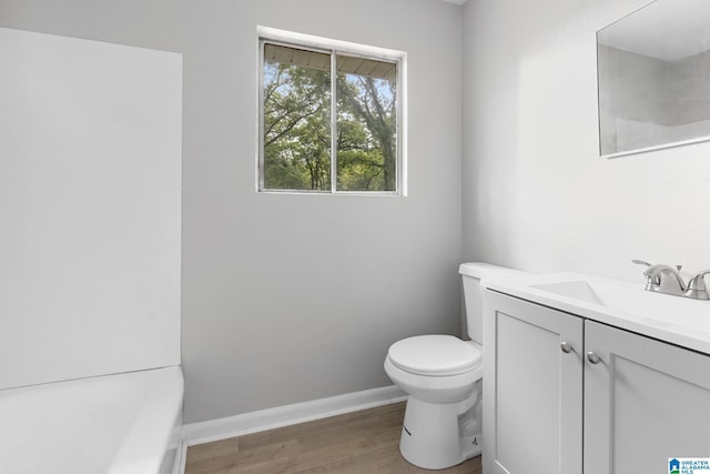 1232 Frisco St, Birmingham, AL 35224 - bathroom featuring vanity, toilet, wood finished floors, a tub to relax in, and baseboards