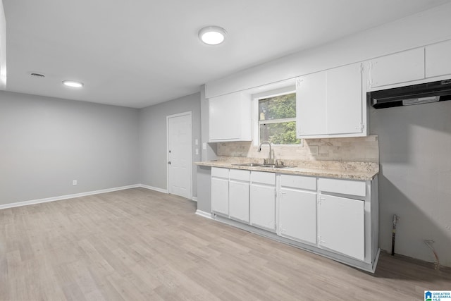 1232 Frisco St, Birmingham, AL 35224 - kitchen featuring a sink, light wood finished floors, decorative backsplash, white cabinets, and baseboards