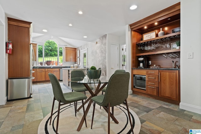 3208 N Woodridge Rd, Mountain Brook, AL 35223 - dining area featuring stone tile flooring, wet bar, wine cooler, lofted ceiling, and baseboards