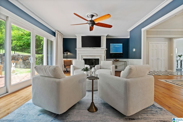3208 N Woodridge Rd, Mountain Brook, AL 35223 - living room with crown molding, a ceiling fan, a brick fireplace, wood finished floors, and a wainscoted wall