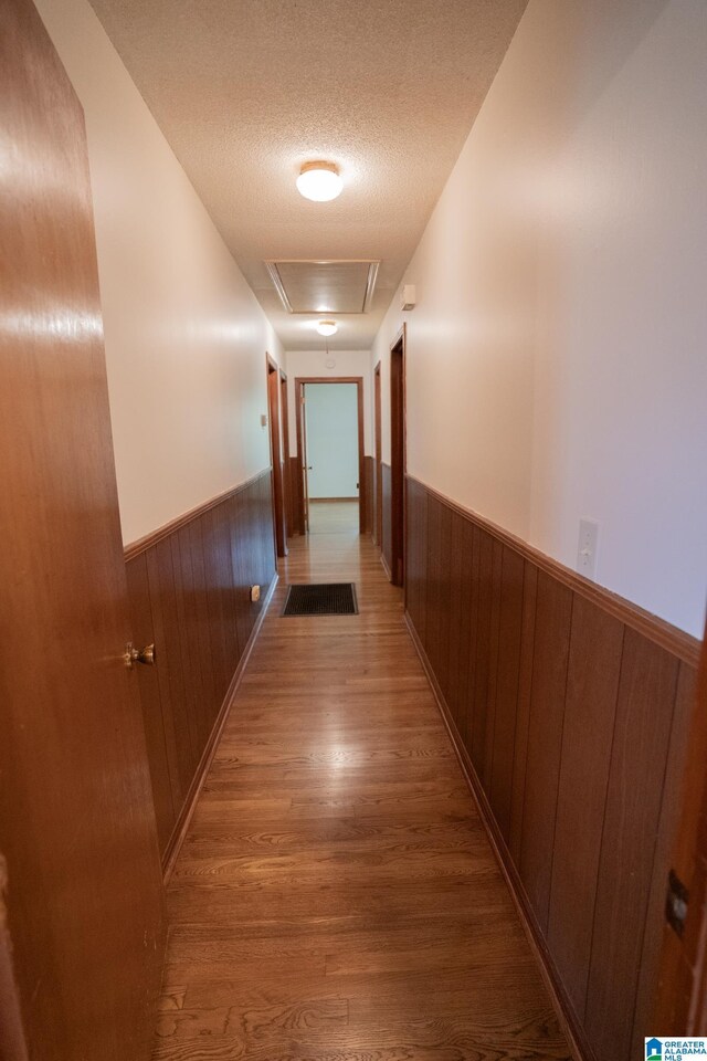 3332 Berry Dr, Hueytown, AL 35023 - hallway with wainscoting, wood finished floors, wood walls, and a textured ceiling