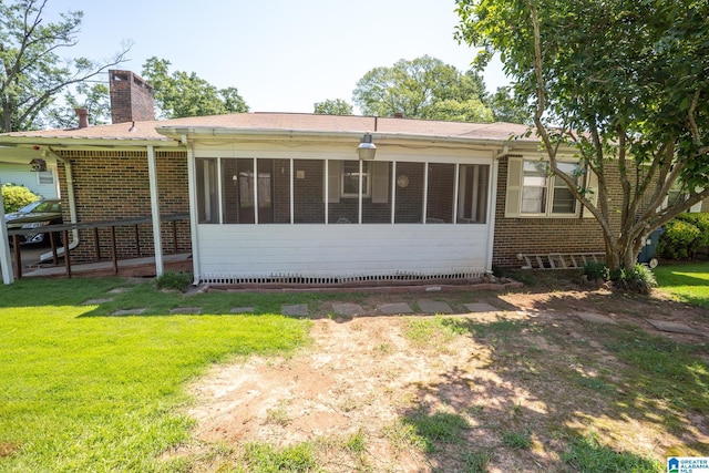 3332 Berry Dr, Hueytown, AL 35023 - rear view of house with a chimney, brick siding, a sunroom, and a yard