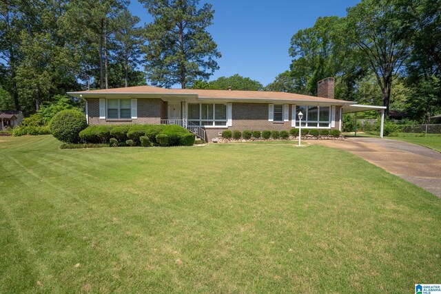 3332 Berry Dr, Hueytown, AL 35023 - view of front facade with a chimney, brick siding, a front lawn, an attached carport, and driveway