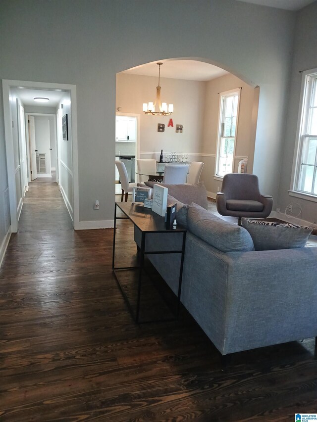 2120 Brewster Rd, Birmingham, AL 35235 - living area with arched walkways, a chandelier, dark wood finished floors, baseboards, and healthy amount of natural light