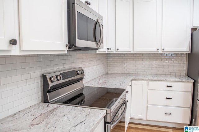 126 Harbor Pointe Dr, Talladega, AL 35160 - kitchen featuring stainless steel appliances, white cabinetry, tasteful backsplash, and light stone counters