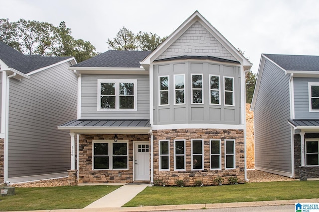 126 Harbor Pointe Dr, Talladega, AL 35160 - view of front of house with stone siding, a front yard, a standing seam roof, a shingled roof, and a metal roof