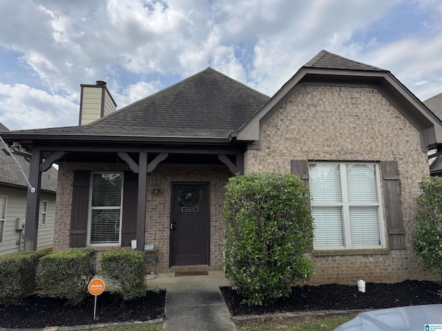 1206 Savannah Ln, Calera, AL 35040 - view of front of house with roof with shingles, brick siding, a chimney, and covered porch