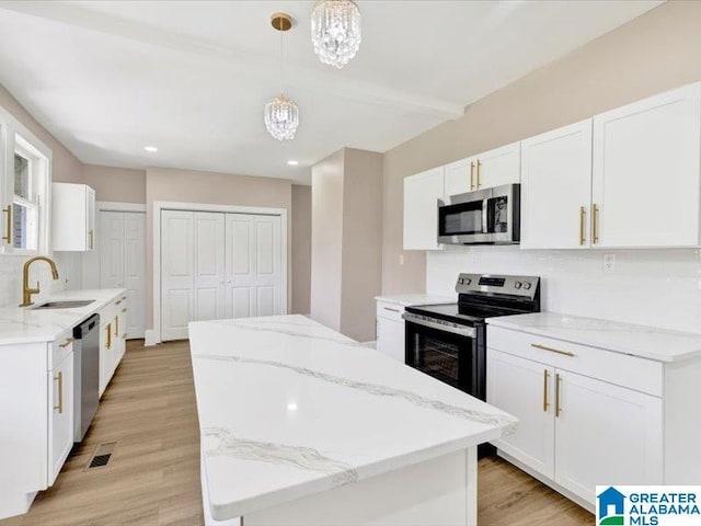 1320 33rd St N, Birmingham, AL 35234 - kitchen with appliances with stainless steel finishes, a sink, a kitchen island, a chandelier, and light stone countertops