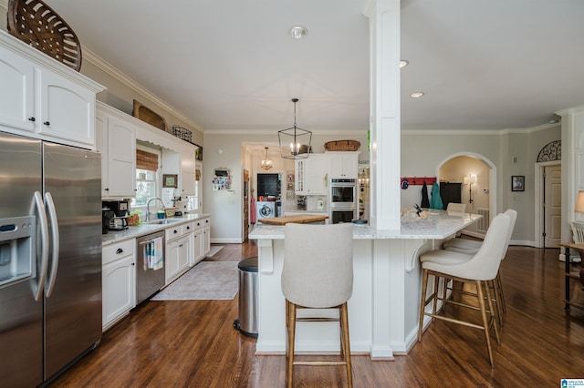 312 La Playa Pl, Homewood, AL 35209 - kitchen with stainless steel appliances, a sink, arched walkways, white cabinets, and dark wood-type flooring