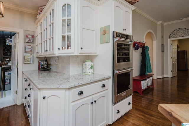 312 La Playa Pl, Homewood, AL 35209 - kitchen with stainless steel double oven, dark wood-style floors, glass insert cabinets, ornamental molding, and backsplash