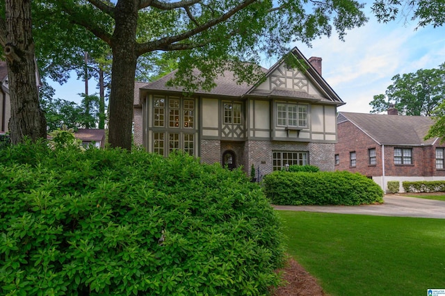 312 La Playa Pl, Homewood, AL 35209 - tudor home featuring stucco siding, brick siding, a chimney, and a front yard