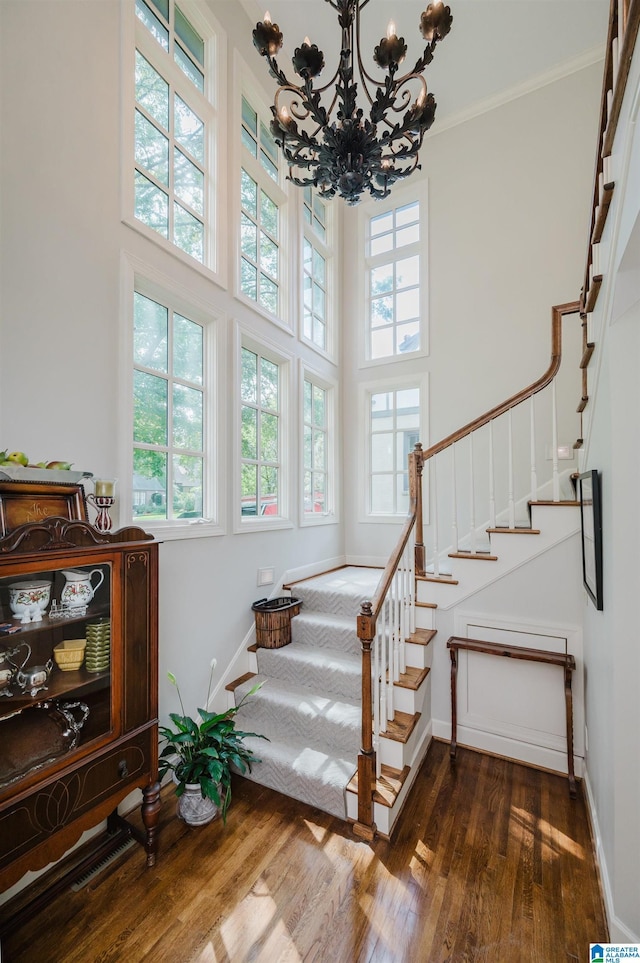 312 La Playa Pl, Homewood, AL 35209 - stairway featuring wood finished floors, a towering ceiling, a chandelier, baseboards, and crown molding