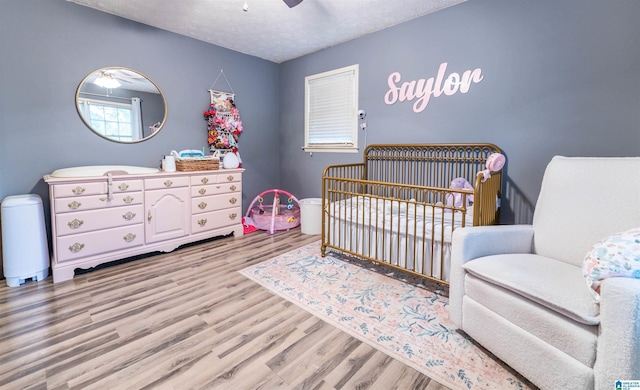 1214 Wildoak Dr, Anniston, AL 36206 - bedroom with a nursery area, wood finished floors, a textured ceiling, and ceiling fan