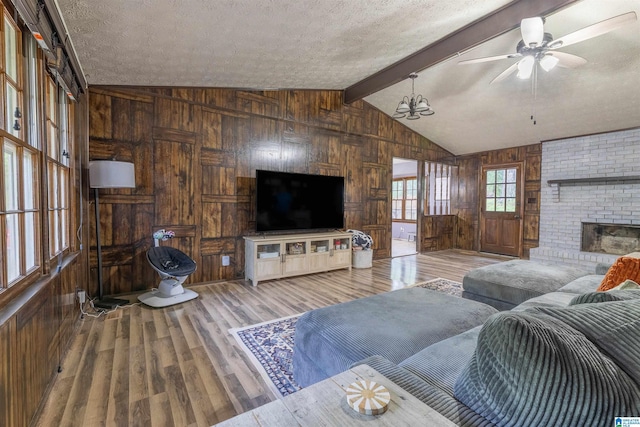 1214 Wildoak Dr, Anniston, AL 36206 - living room with wooden walls, wood finished floors, ceiling fan, a brick fireplace, and a textured ceiling