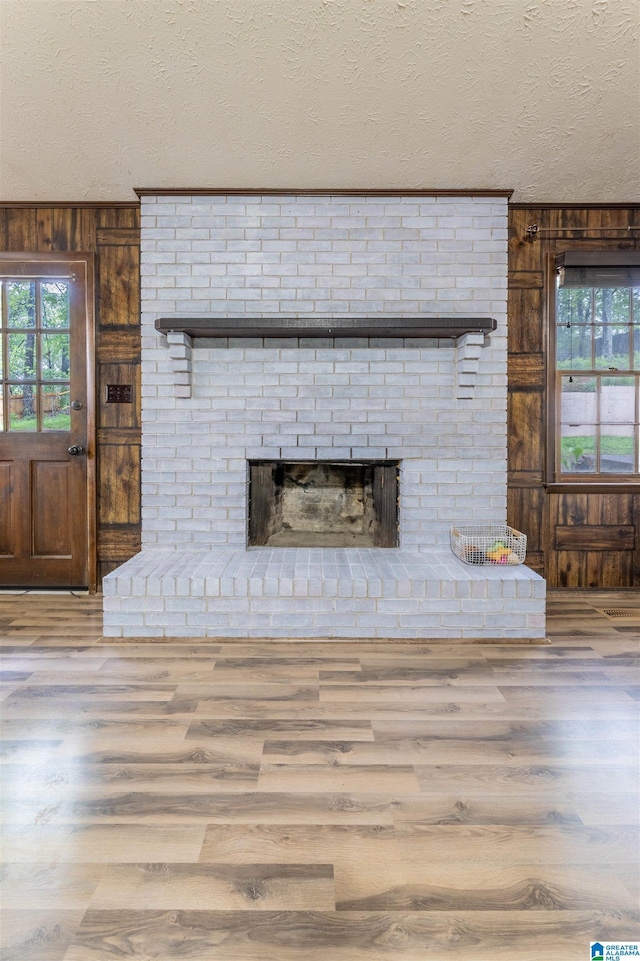 1214 Wildoak Dr, Anniston, AL 36206 - detailed view of wood finished floors, a textured ceiling, wood walls, and a brick fireplace
