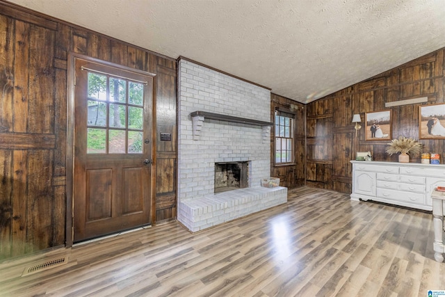 1214 Wildoak Dr, Anniston, AL 36206 - unfurnished living room featuring a textured ceiling, plenty of natural light, wood walls, wood finished floors, and lofted ceiling