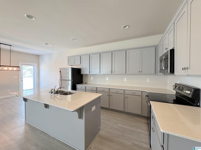 115 Ridgeview Cir, Jemison, AL 35085 - kitchen with appliances with stainless steel finishes, a sink, light wood-type flooring, a kitchen island with sink, and a kitchen breakfast bar
